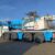 Camion-grue bleu stationné sur un parking industriel