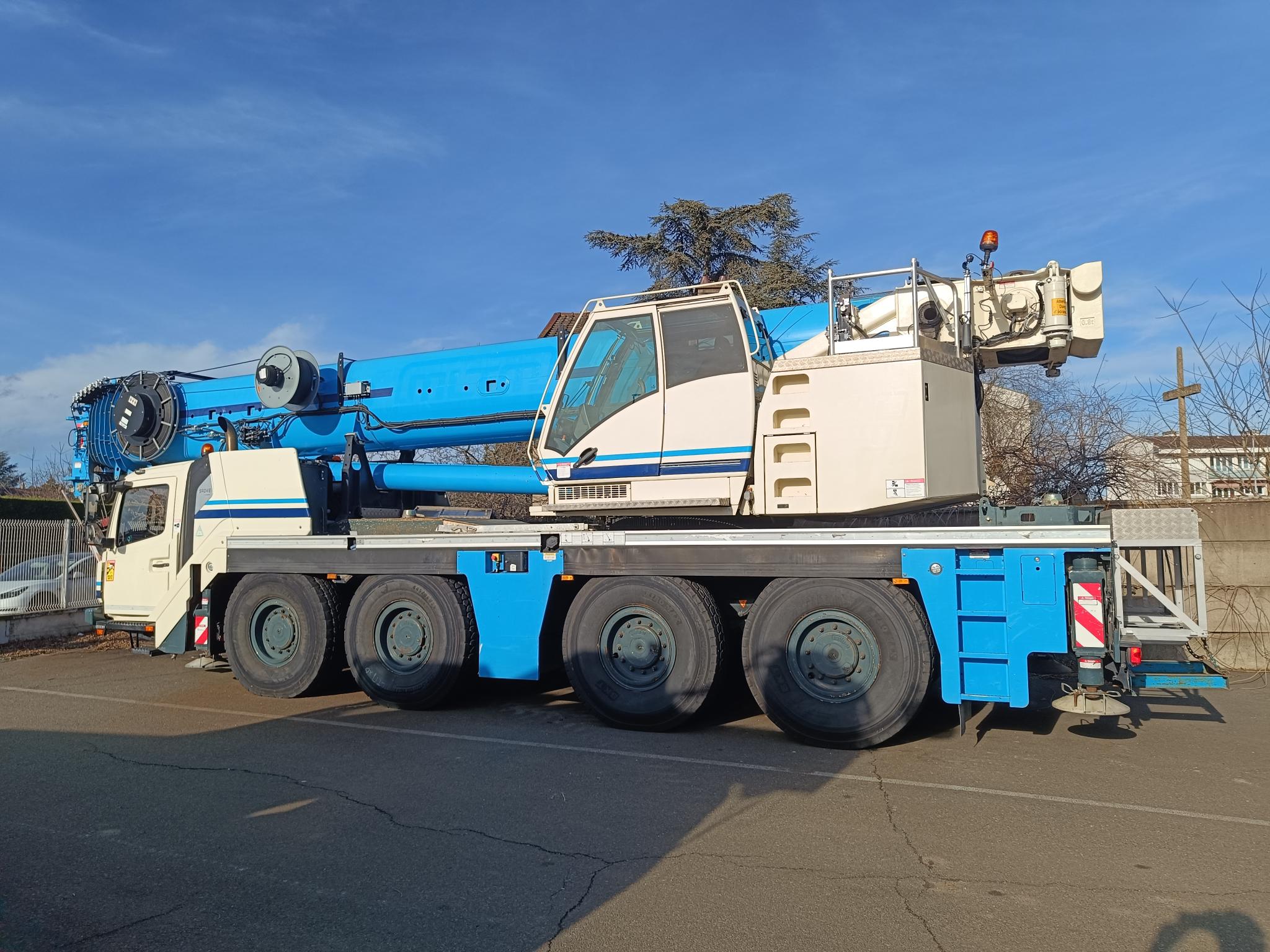 Camion-grue bleu stationné sur un parking industriel